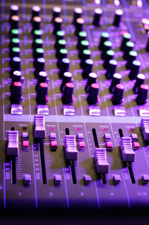 Closeup image of a soundboard used for music lit by purple light